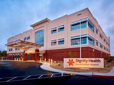 The front exterior of Dignity Health Hospital against a purple evening sky.