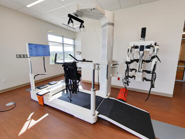 A gait treatmill with overhead suspension harness in a therapy gym.