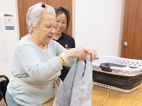 After stoke, a patient learns to rebuild everyday skills through occupational therapy as she folds laundry with her therapist.