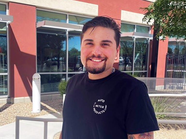 Chris Mann stands in front of the columns and glass windows at Dignity Health Rehabilitation Hospital, smiling for the camera.