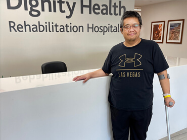 Jarell Geaga stands at the front desk in the hospital lobby.